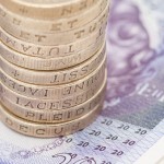 Pound coins stacked up on top of some £20 notes.
